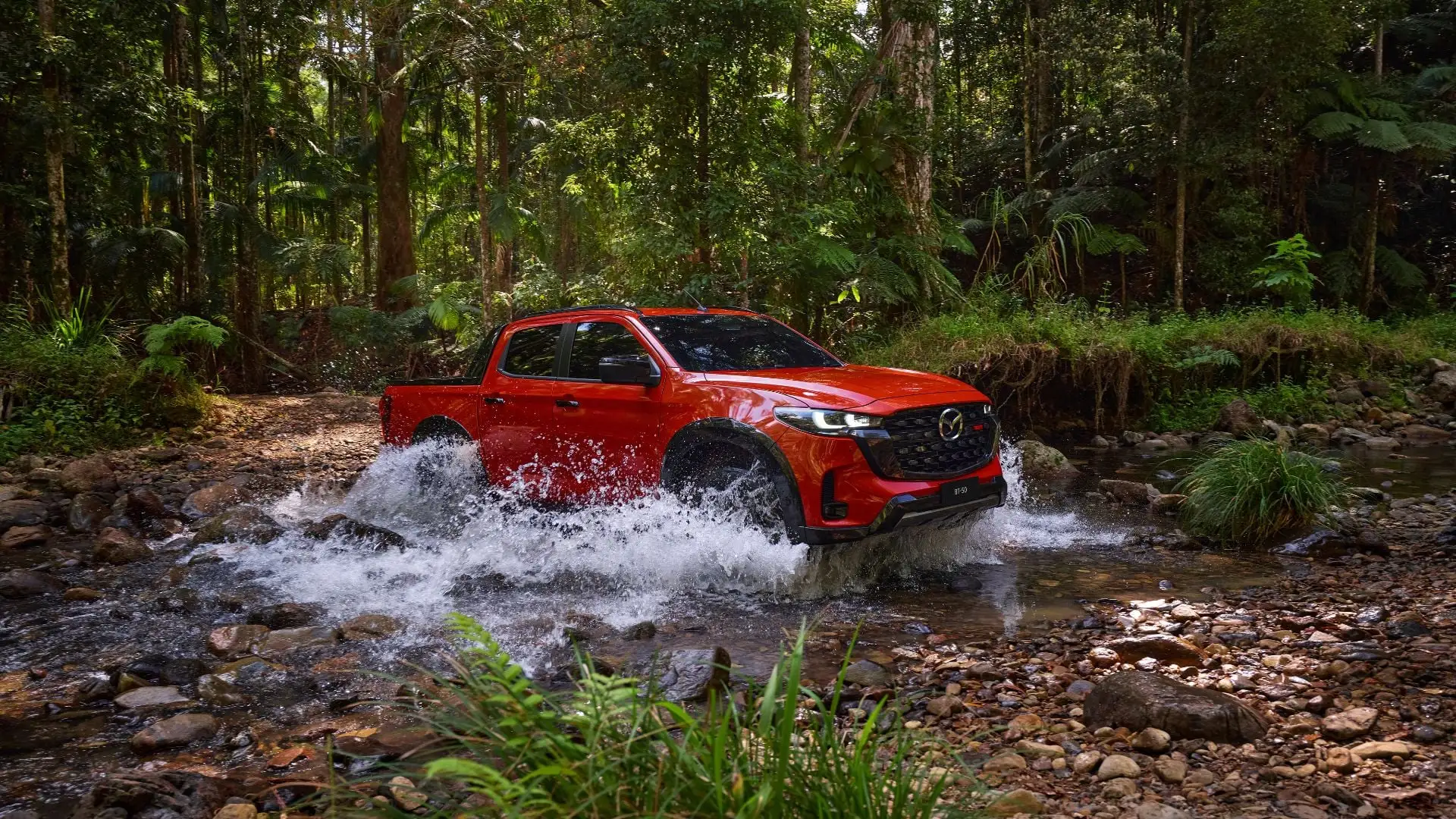 Camioneta Mazda BT-50 roja cruzando un río en plena marcha